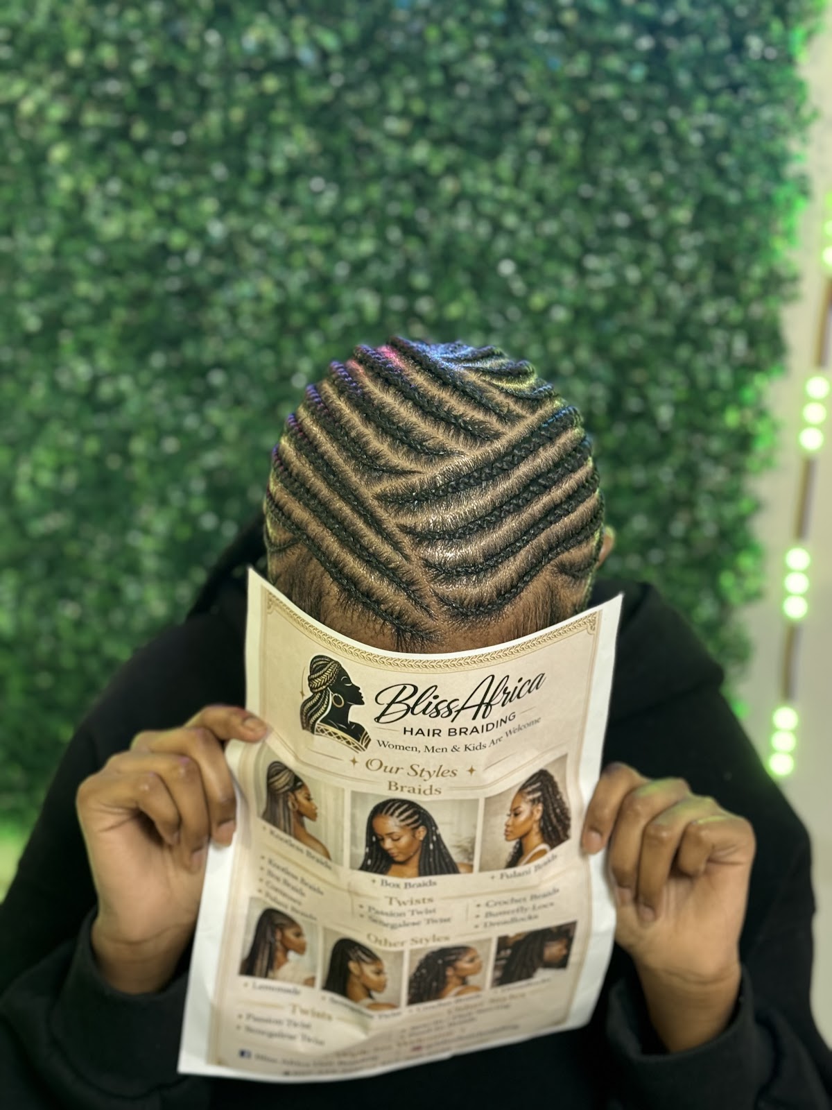 Man showcasing fresh diagonal stitch braids while holding the Bliss Africa service menu